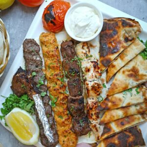 A mouth-watering assortment of grilled meats served with pita bread and fresh lemon.