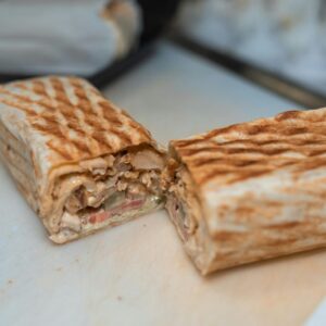 Close-up of a freshly grilled shawarma wrap halved to reveal its appetizing ingredients.