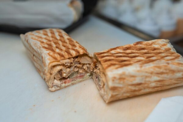 Close-up of a freshly grilled shawarma wrap halved to reveal its appetizing ingredients.