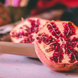 Vibrant pomegranate halves showcasing juicy seeds on a rustic table.