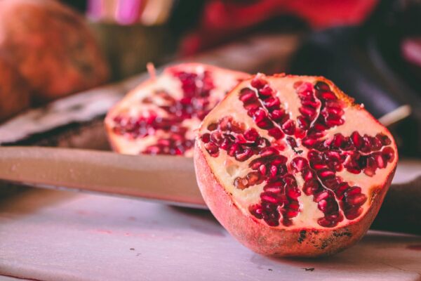 Vibrant pomegranate halves showcasing juicy seeds on a rustic table.