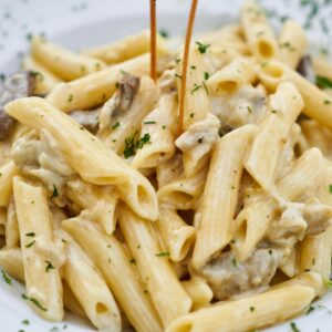 Close-up of creamy pasta with herbs, offering a delicious Italian meal.