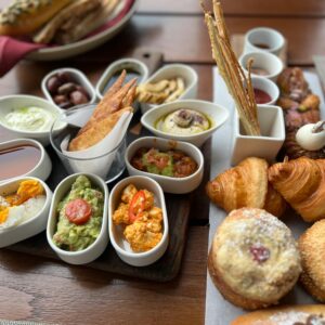 Delicious assortment of gourmet brunch items including croissants, bagels, and Mediterranean dips.