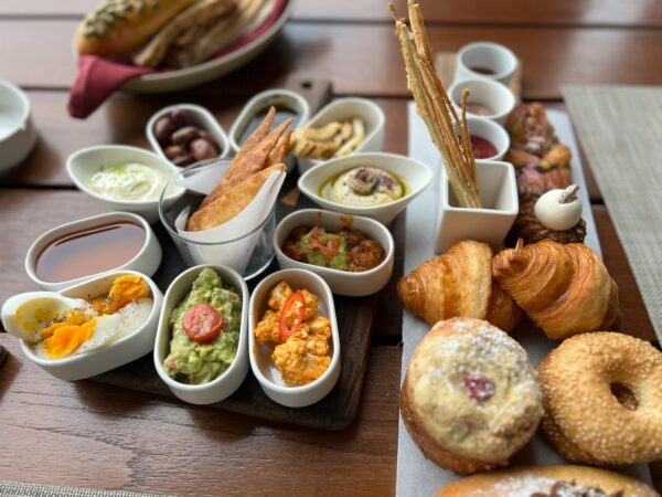 Delicious assortment of gourmet brunch items including croissants, bagels, and Mediterranean dips.