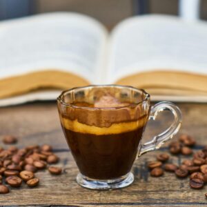 A rich espresso cup surrounded by beans and an open book, perfect for a relaxing break.