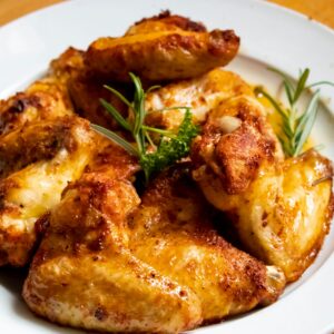 Golden-brown chicken wings garnished with fresh herbs, perfect for a tasty meal.