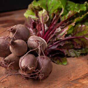 Bundle of fresh organic beetroots with vibrant green leaves on a wooden surface.