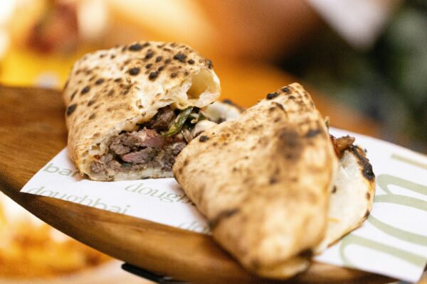 Close-up of a flavorful folded flatbread stuffed with savory ingredients on a wooden board.
