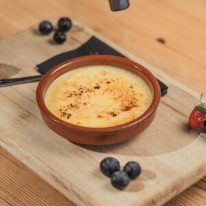 Delicious creme brulee served with fresh berries on a wooden board.