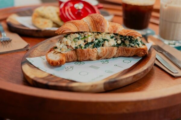Delicious croissant stuffed with spinach and cheese served on a wooden plate, perfect for a hearty breakfast.