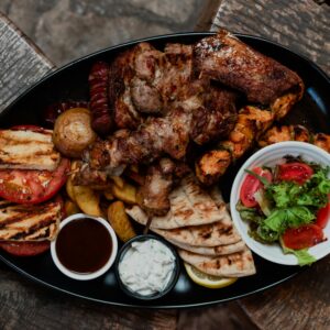 A vibrant platter showcasing various grilled meats, fresh vegetables, and sauces.