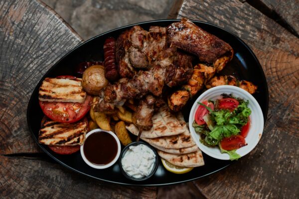 A vibrant platter showcasing various grilled meats, fresh vegetables, and sauces.