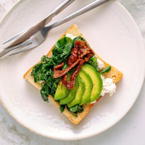 Savor this healthy avocado and spinach toast served on a marble table, perfect for breakfast.