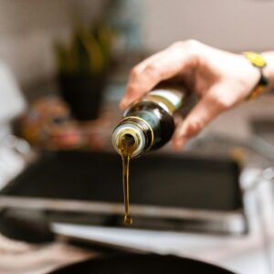 A focused image showing olive oil being poured from a bottle into a pan during cooking.