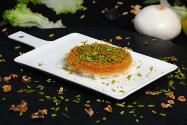 Close-up of mouthwatering Arabic Kunafa topped with chopped pistachios.