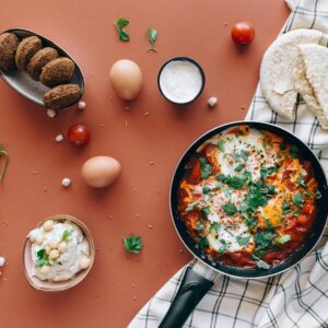 Flat lay of Middle Eastern breakfast featuring shakshuka, falafel, pita, and hummus.