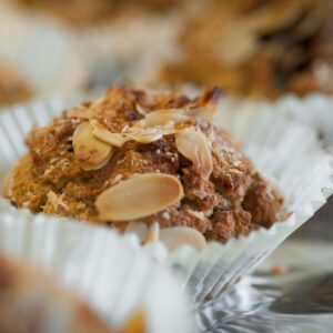 Tempting close-up shot of a tasty almond-topped muffin in a paper liner.